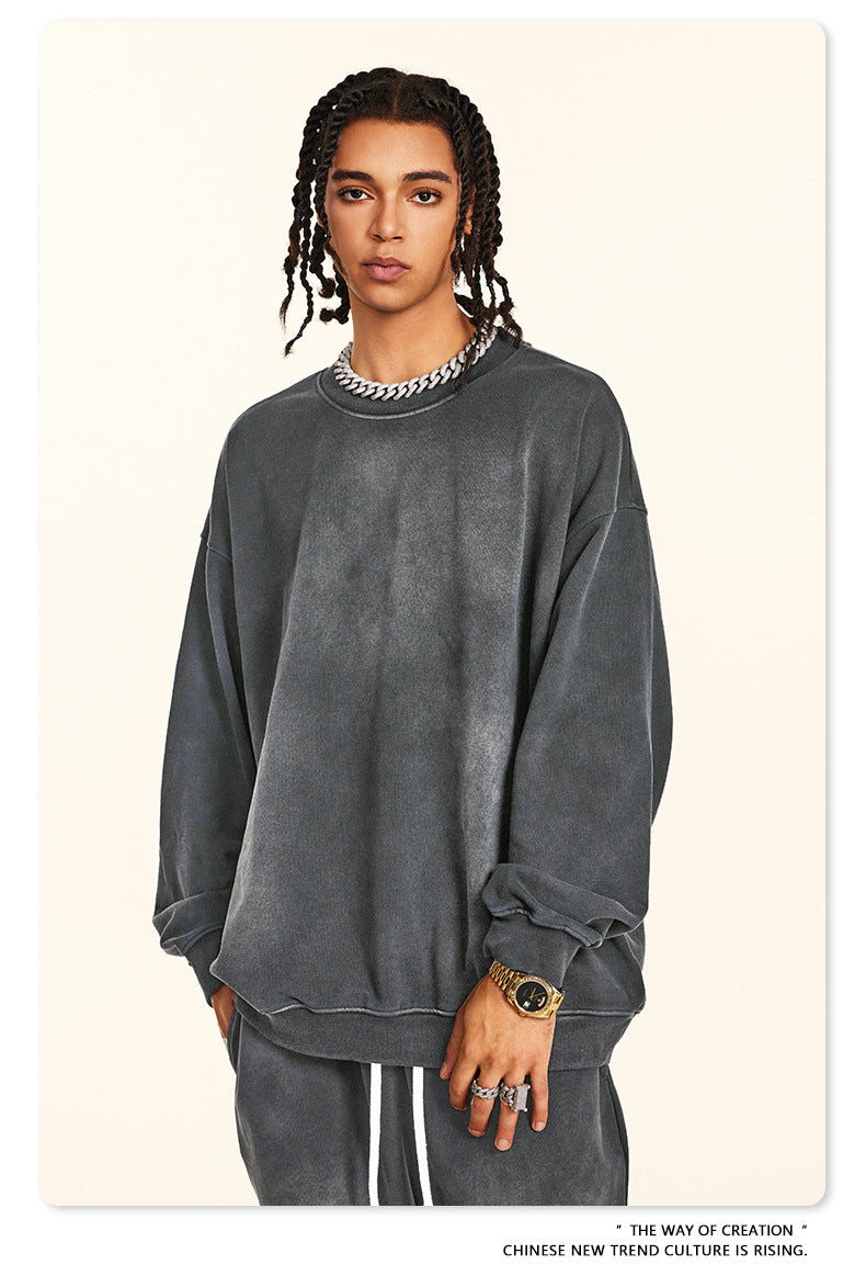 Dark grey oversized sweatshirt with chain accessory and gold watch, showing brushed cotton texture