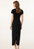 The back view of a stylish woman in a black sleeveless maxi dress, accessorized with a silver necklace.