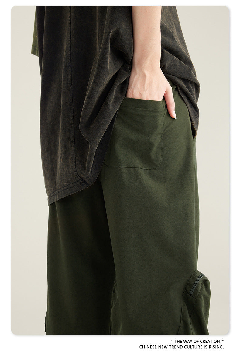 Detail of hand reaching into side pocket of olive green cargo pants with oversized black top