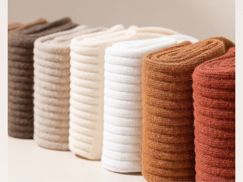 Artfully rolled pure cotton socks in neutral tones from brown to white arranged in a row