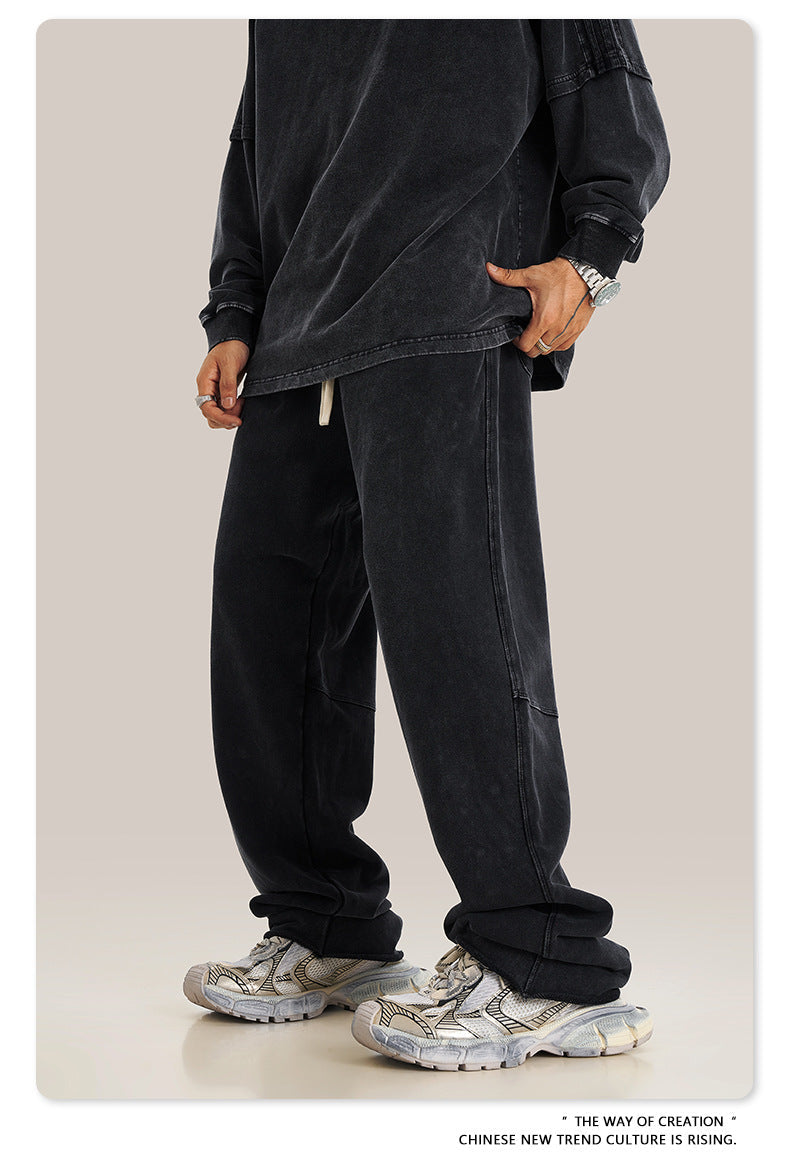 Side profile of black sweatpants with white drawstring, showing detailed panel stitching and relaxed fit