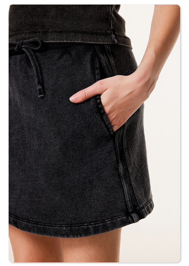 Detail of black mini skirt pocket with model's hand demonstrating functional side pocket design