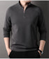 Charcoal gray quarter-zip pullover sweater with standing collar and raglan sleeves, styled with black pants and wristwatch