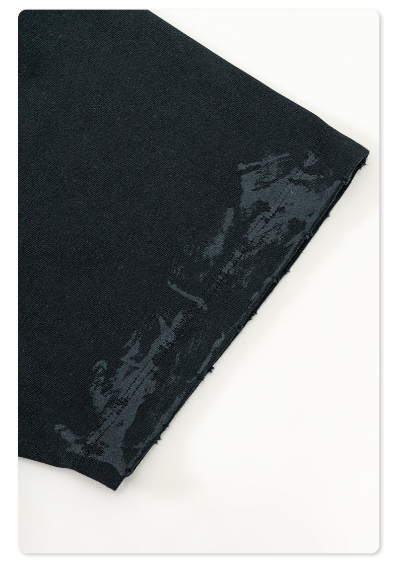 Close-up of black Backstairs sweatpants fabric showing distressed paint-splatter pattern and textile texture
