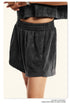 Close-up of black washed shorts with elastic waistband showing texture detail and silver watch
