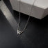 Silver W pendant necklace displayed on black leather texture with white box edge visible