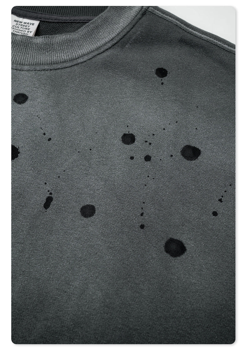 Detailed view of black paint splatter pattern on gray sweatshirt fabric