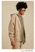 Side profile of man wearing beige zip-up hoodie, olive shirt and silver chain necklace