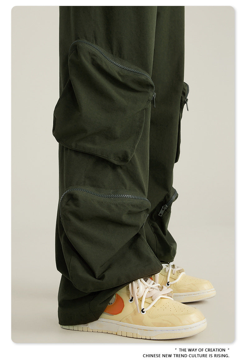 Close-up of olive green cargo pants pocket detail with zippered utility pouch and cream sneakers with orange detail