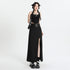 Model wearing black tank top and maxi skirt with silver belt detail, styled with platform shoes against white backdrop