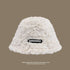 White faux fur bucket hat with a "Doraemon" logo patch, offering a cozy and stylish winter accessory