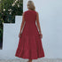 A woman is wearing a burgundy maxi dress with tiered skirt design, shown from back view against a white stucco wall