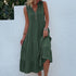 A woman is wearing an olive green sleeveless tiered dress with button front detail, lifting the fabric against a white wall