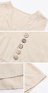 A detailed view of beige dress fabric showing v-neckline stitching and decorative button details with clean hem finishing