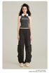 Model with curly dark hair wearing vintage-wash tank top with text graphic and black cargo pants with utility pockets on neutral background