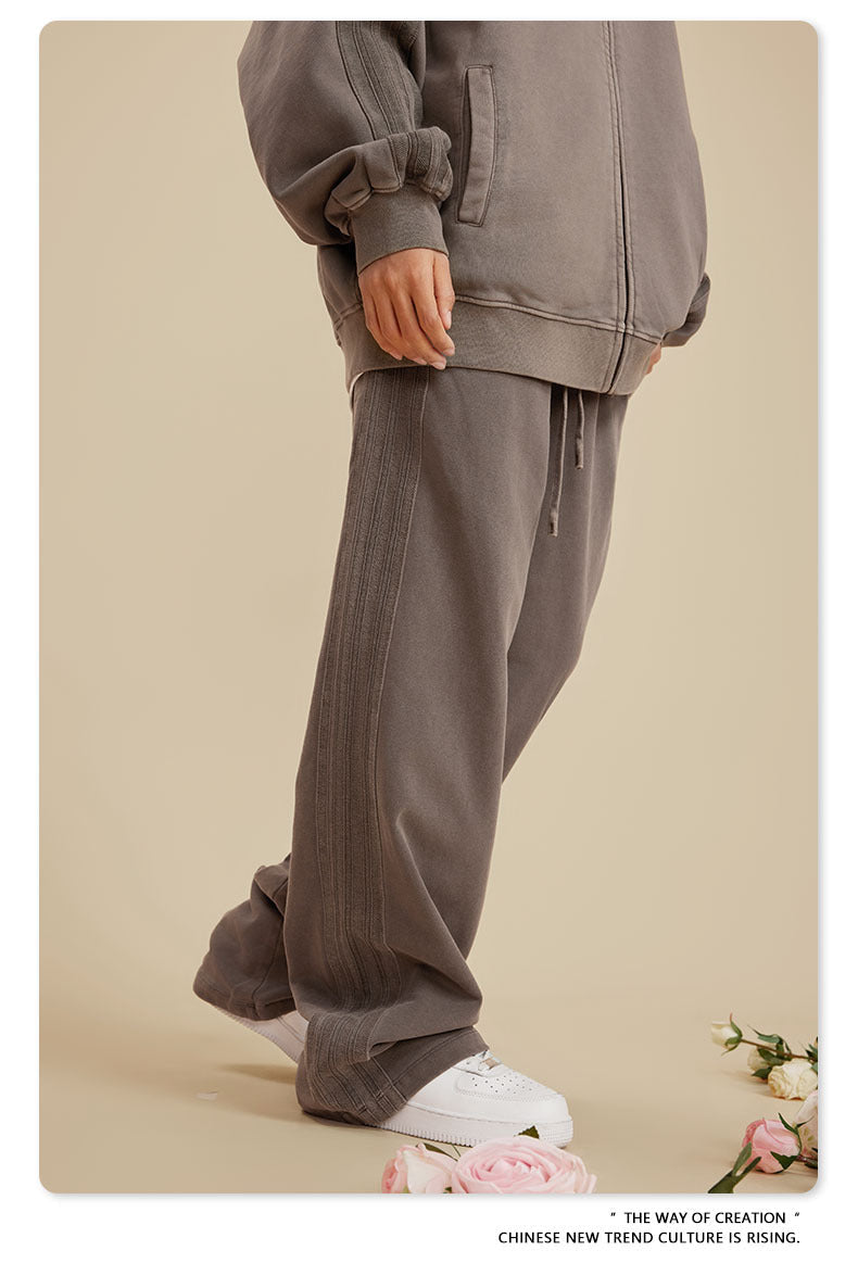 Side profile showing grey zip-up jacket sleeve and drawstring sweatpants with white sneakers on beige background with roses