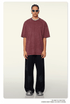 Model wearing burgundy oversized t-shirt with black wide-leg pants, white sunglasses and silver chain necklace against beige background