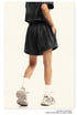 Side view of black cotton shorts with elastic waist, showing relaxed fit with white athletic socks