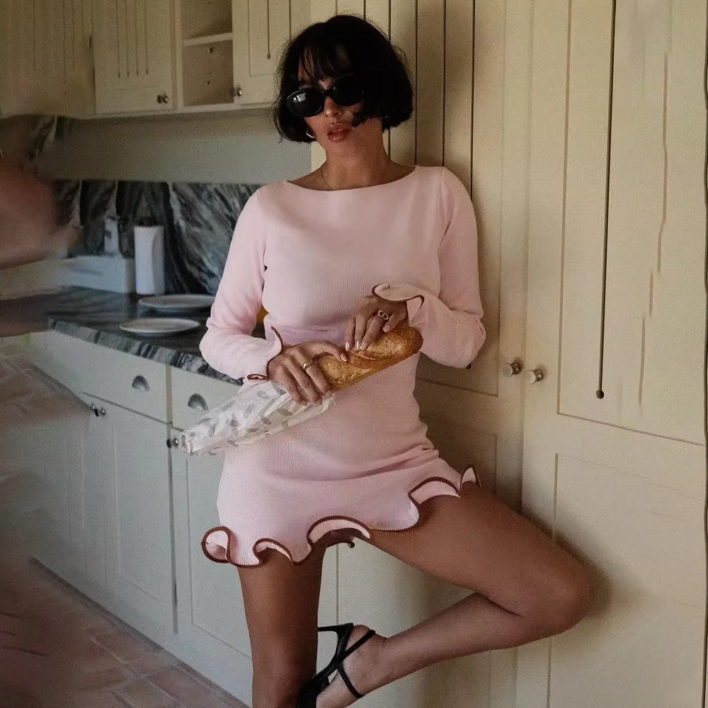 Woman in pink long-sleeve mini dress with contrasting ruffle trim, wearing sunglasses and holding baguette