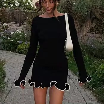 Black fitted mini dress with white contrast ruffle trim on sleeves and hem, worn with white crossbody bag