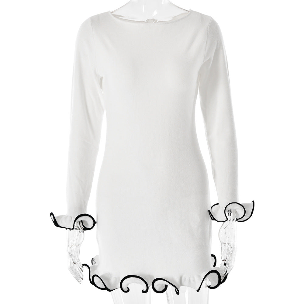 White long-sleeve mini dress with black decorative ruffle trim on display, featuring boat neckline