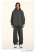 Model in dark gray hoodie and sweatpants set with twisted braids and white sneakers on neutral backdrop
