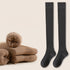Dark charcoal knee-high socks displayed with stacked beige socks and red indicator button