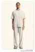 Model in cream two-piece set featuring oversized t-shirt and wide-leg pants with subtle wash effect. Styled with silver chain necklace and statement watch