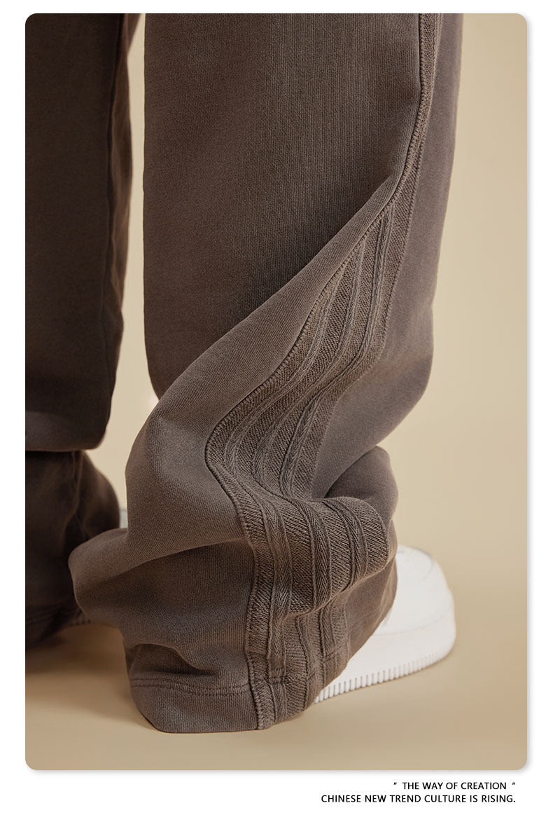 Close-up of grey sweatpants leg with textured ribbed side panel detail and white sneaker visible at bottom
