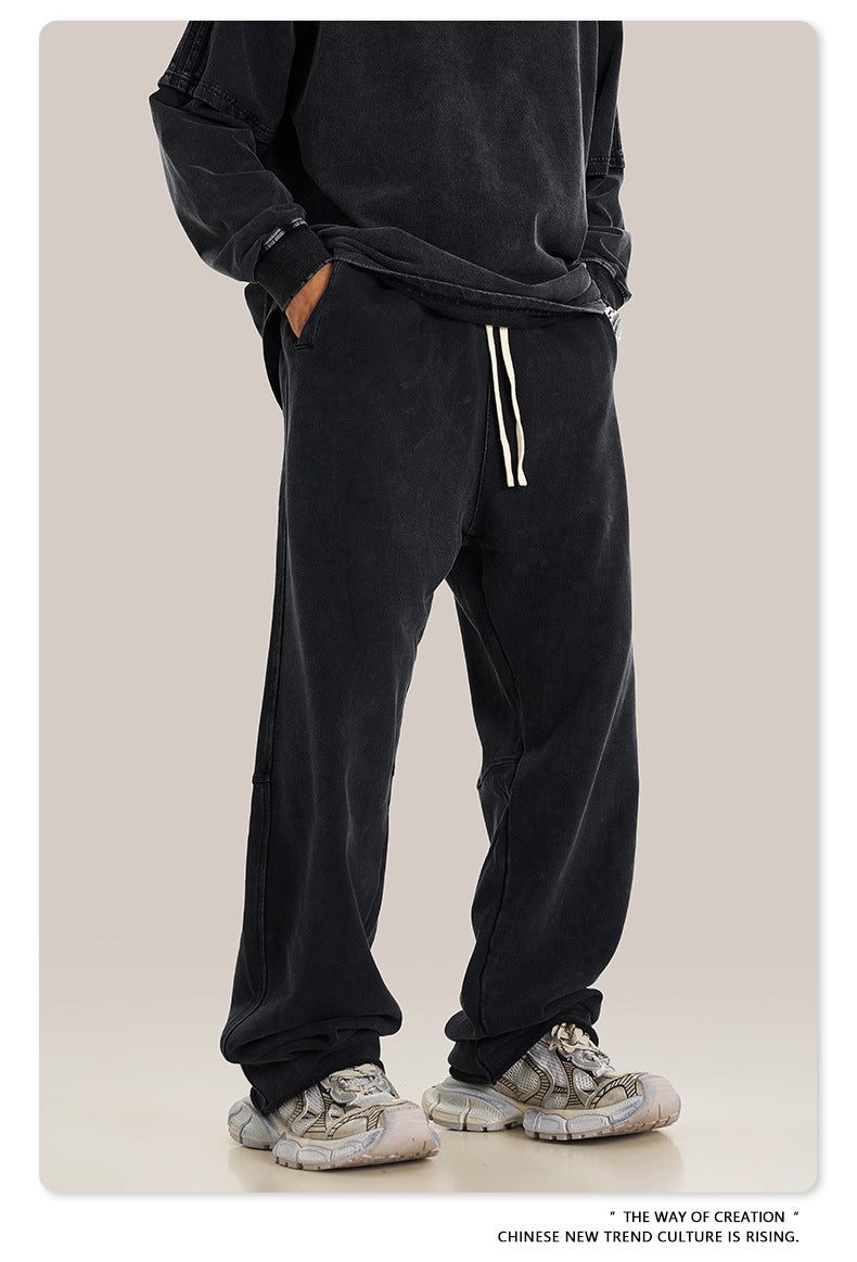 Person wearing black hoodie and navy blue sweatpants with white drawstring, showing side profile of the pants' fit