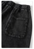 Close-up of elastic waistband and back pocket detail on black track pants against white studio background
