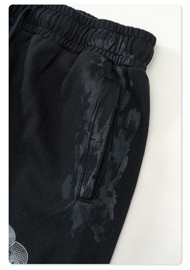 Close-up of black Backstairs sweatpants showing pocket, waistband elastic and drawstring against white background