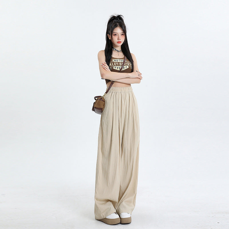 A model wearing a brown Harley-Davidson crop top and beige wide-leg palazzo pants with elastic waist, styled with platform sneakers