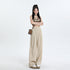 A model wearing a brown Harley-Davidson crop top and beige wide-leg palazzo pants with elastic waist, styled with platform sneakers
