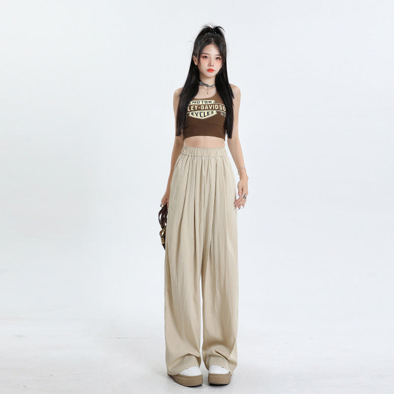Full-length view of beige palazzo pants with elastic waist and wide-leg silhouette, paired with white platform sneakers