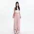 Model in white star-print crop top and pink wide-leg pants, accessorized with pink shoulder strap and matching sneakers