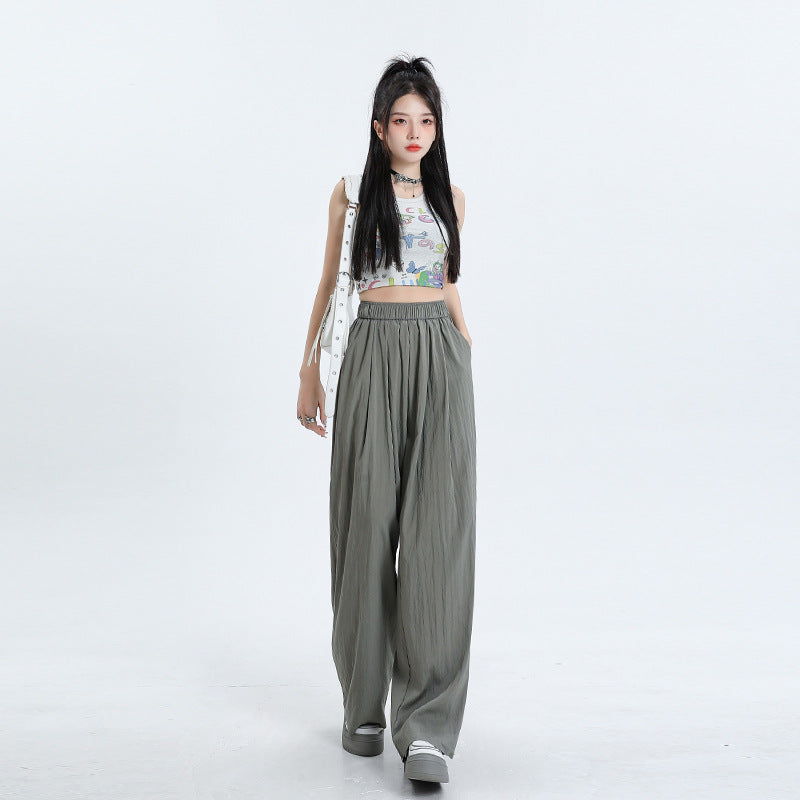 Model in white graphic print crop top and olive green wide-leg pants with elastic waist, styled with white platform shoes