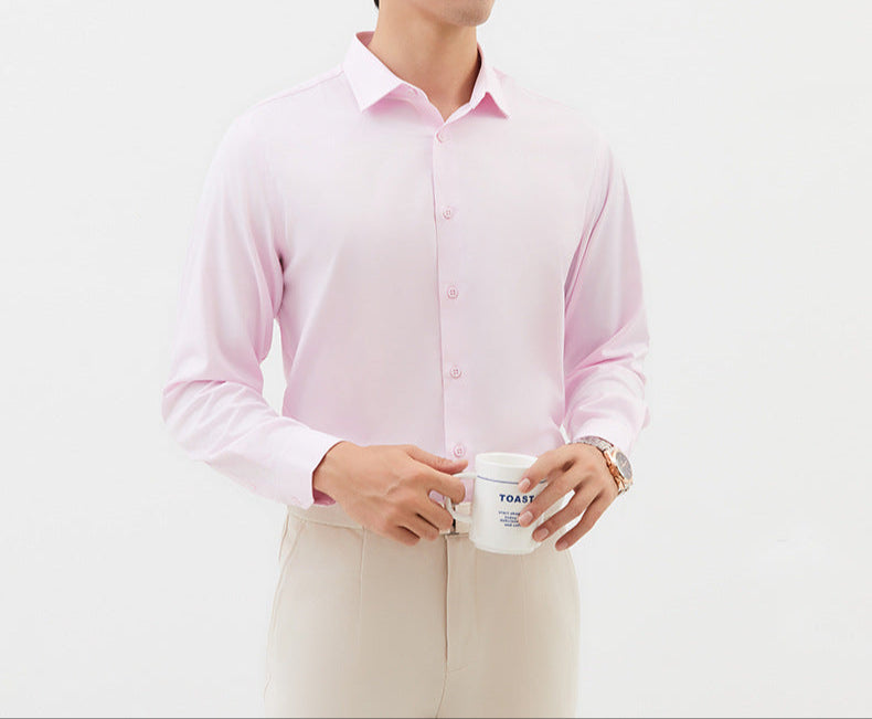 A model is holding a white coffee mug while wearing a light pink dress shirt and cream trousers. Gold watch visible on wrist
