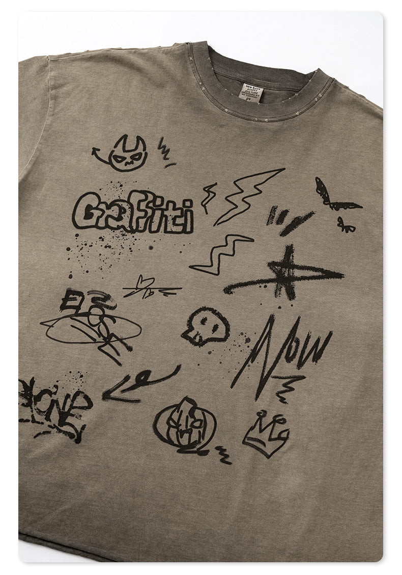 Close-up of graffiti print featuring skull, lightning bolt, and 'Graffiti' text graphics on taupe cotton tee