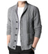 Close-up view of light gray shawl collar cardigan showing detailed cable knit pattern, black button placket, and patch pocket detail