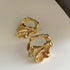 Sculptural Gold Hoop Earrings – Artistic gold earrings with an irregular molten-metal design, set against a neutral background