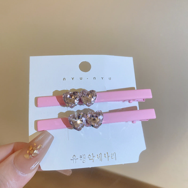 Assorted pink and silver hair clips with star, heart, bow, and gemstone designs, laid out on a fabric surface.