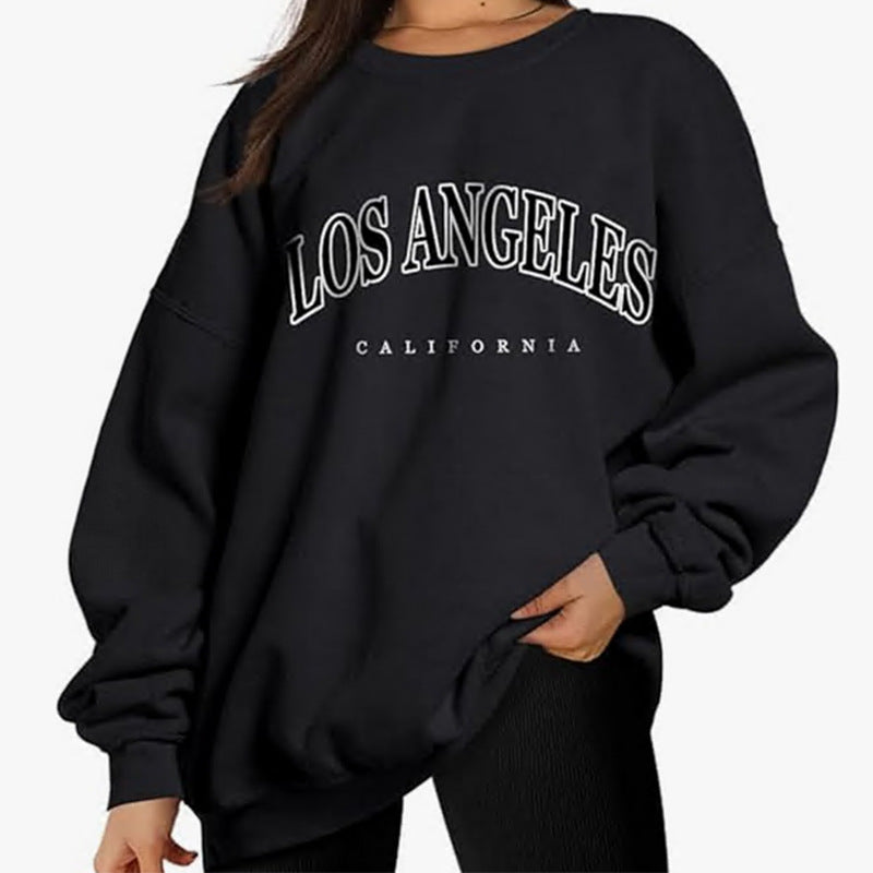 A black oversized sweatshirt with white 'LOS ANGELES CALIFORNIA' text graphic, shown on model with black leggings against white backdrop