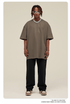Man with short dreadlocks wearing taupe oversized t-shirt, black sweatpants, white sneakers, silver chain necklace and white-framed sunglasses