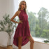 A woman with blonde hair is wearing a burgundy halter dress and posing with legs apart, showing the high-low hem