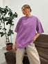 Person wearing an oversized purple shirt in a casual indoor setting