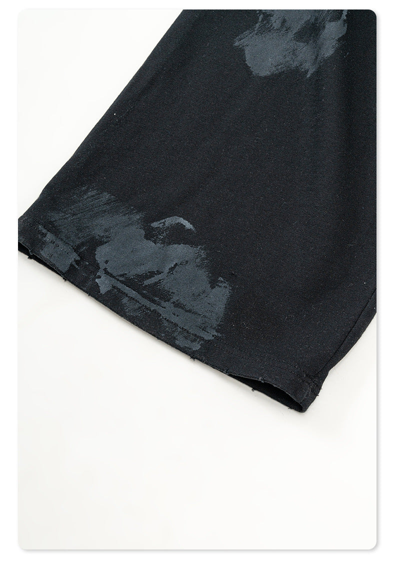 Distressed black Backstairs sweatpants fabric showing uneven paint effect pattern and texture details