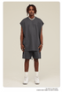 Male model in dark gray matching set with oversized muscle tee, drawstring shorts and silver chain necklace