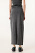 Rear view of long dark gray denim skirt with center back seam, worn with black and gray sneakers and cream socks