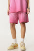 A person wearing bright pink washed cotton shorts with matching top and cream athletic shoes against white background